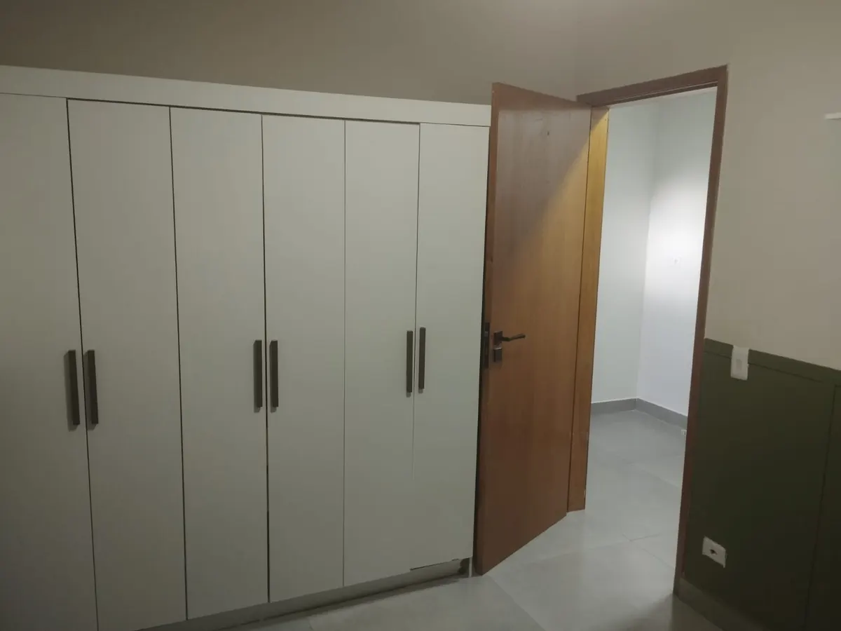 Armário planejado branco e porta de madeira em quarto entregue